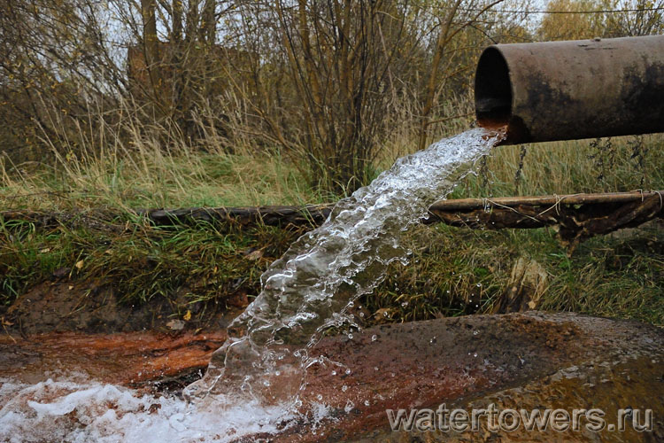 Поток воды из трубы в нижней части водонапорной башни
